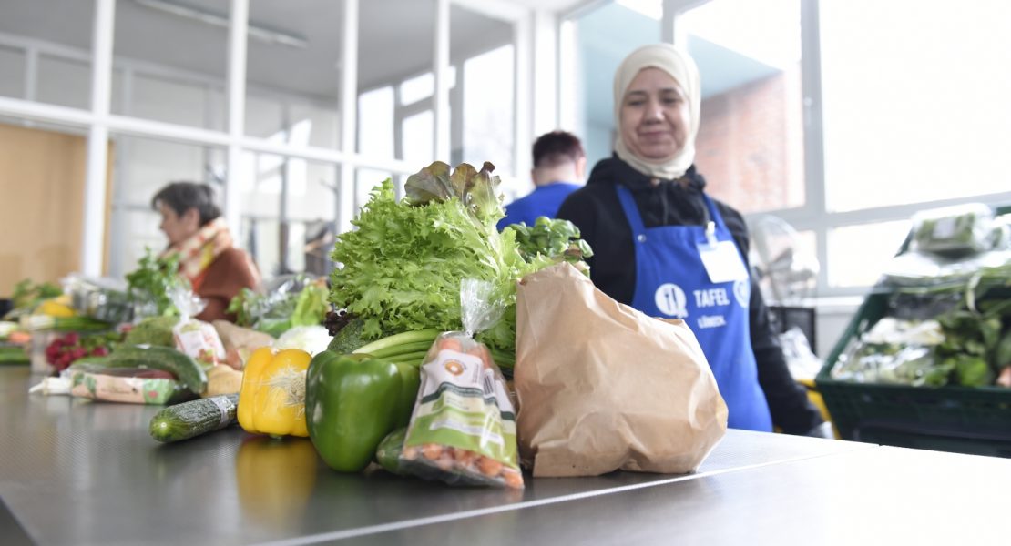 Eine Tafel-Helferin schaut lächelnd auf Gemüse.