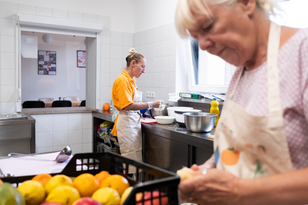 2 Frauen bereiten in einer Tafel-Küche Lebensmittel zu.