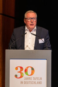 Andreas Steppuhn hält eine Rede. Auf dem Rednerpult ist "30 Jahre Tafeln in Deutschland" zu lesen.