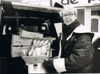 Schwarz-Weiß-Foto von Tafel-Gründerin Sabine Werth, die eine Kiste Zucchini in die Kamera hält.