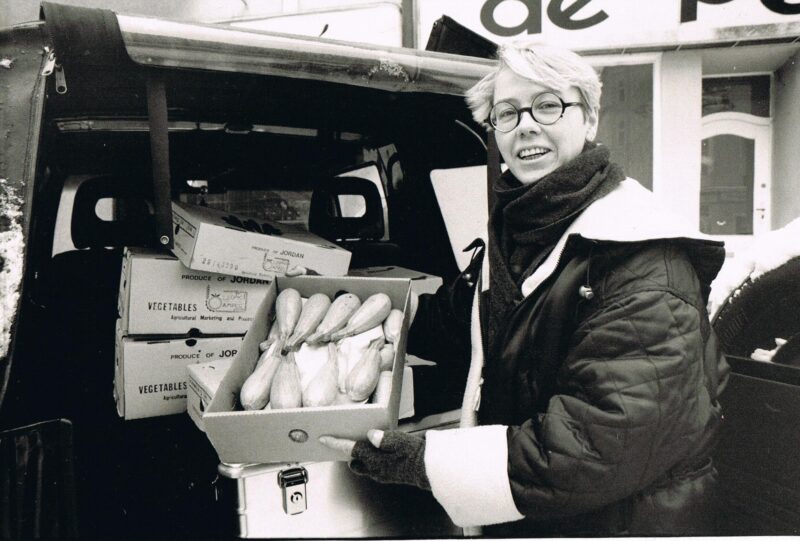 Schwarz-Weiß-Foto von Tafel-Gründerin Sabine Werth, die eine Kiste Zucchini in die Kamera hält.