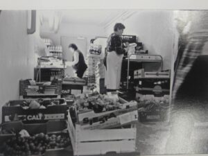 Schwarz-Weiß-Foto von Tafel-Helfer:innen, die Lebensmittel sortieren