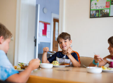 Drei Kinder sitzen gemeinsam am Tisch und essen ihre selbstgemachte Mahlzeit