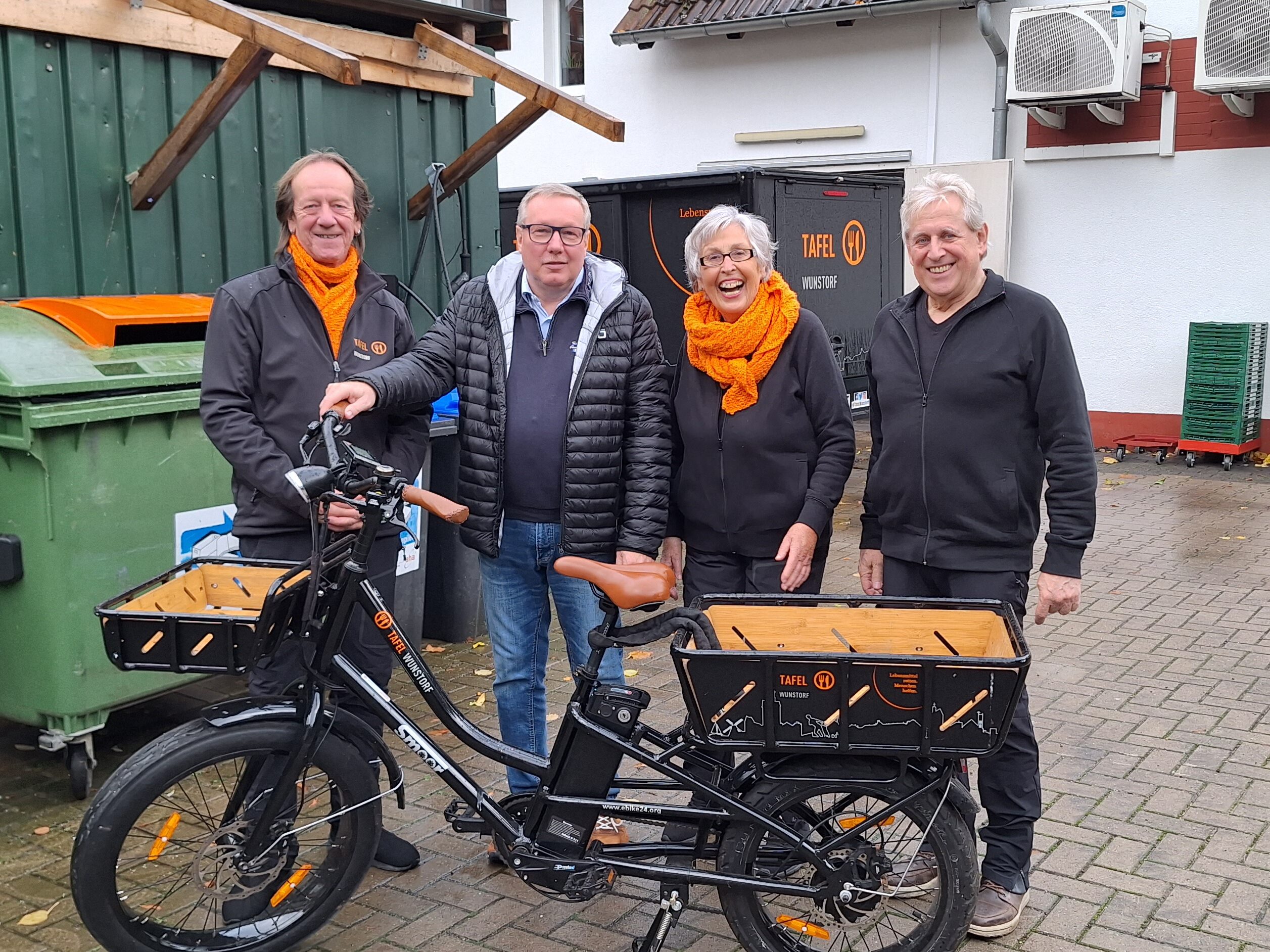 Andreas Steppuhn steht vor einem E-Bike mit 3 Engagierten aus dem Vorstand der Tafel Wunstorf