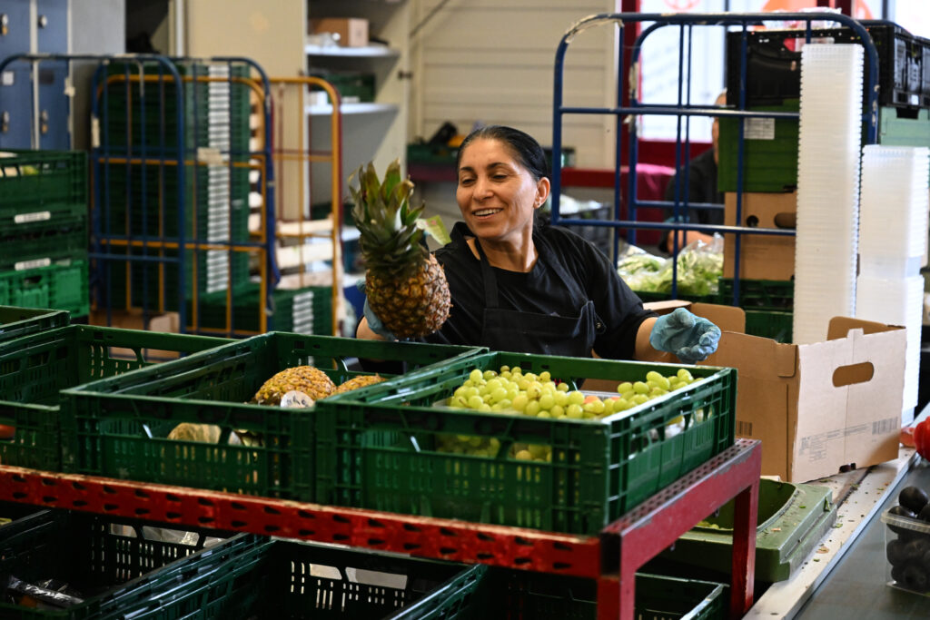 Eine Tafel-Helferin legt eine Ananas in eine Kiste.