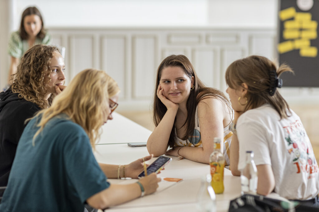 4 junge Tafel-Aktive sitzen an einem Tisch und sprechen miteinander.