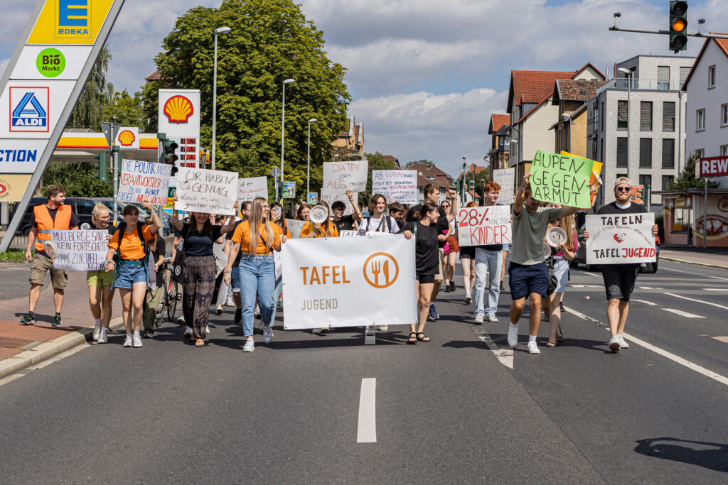 Junge Tafel-Aktive laufen mit Plakaten gegen Armut und Lebensmittelverschwendung bei einer Demo in Göttingen.