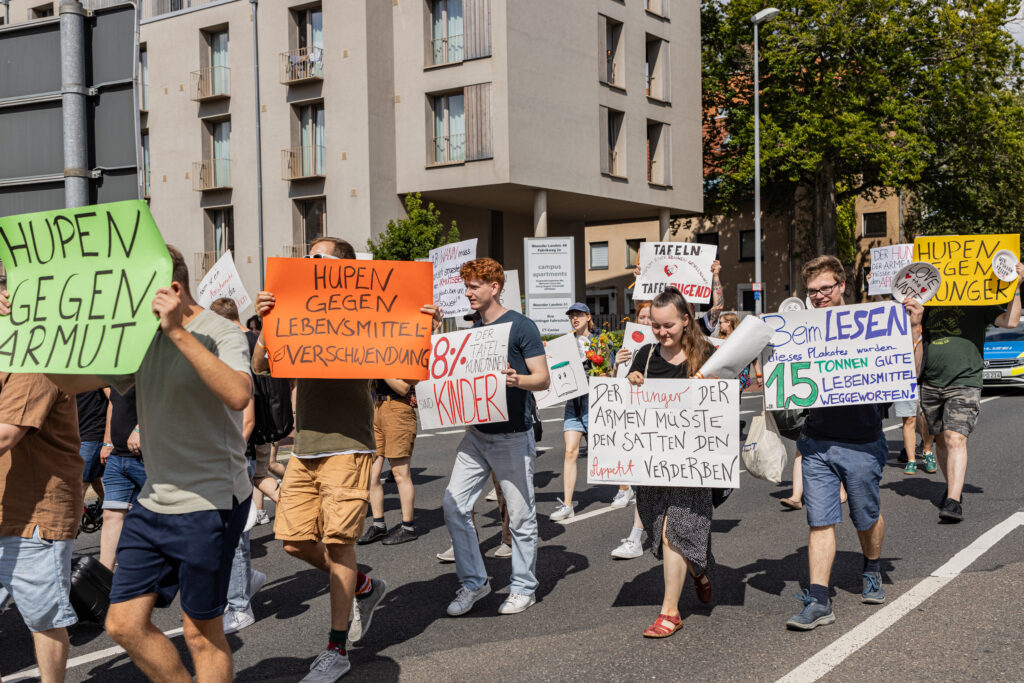 Junge Tafel-Aktive laufen mit Plakaten bei einer Demo in Göttingen.