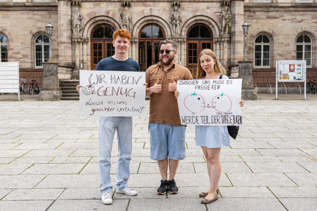 Mika Dietrich, Maximilian Blaeser und Anna-Sophia Majewska posieren in der Göttinger Innenstadt mit Plakaten.