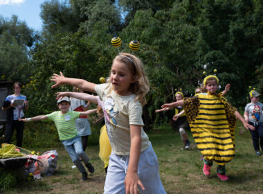 Kinder, die als Bienen verkleidet sind, spielen gemeinsam draußen.