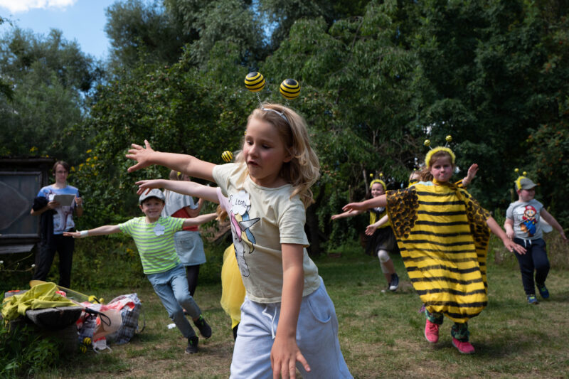 Kinder, die als Bienen verkleidet sind, spielen gemeinsam draußen.