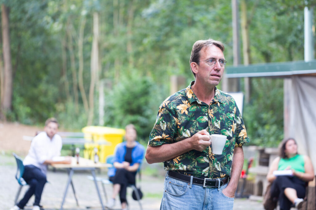 Ein Mann mit einer Tasse in der Hand schaut auf die Bühne. 