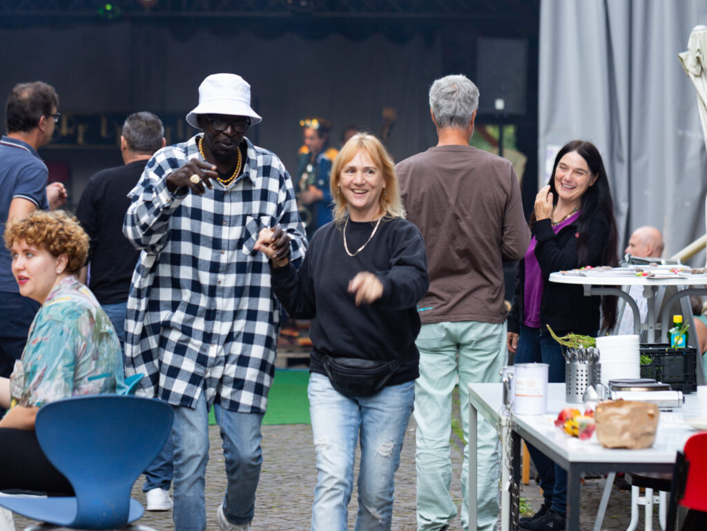 Birgit führt einen Mann an der Hand durch das Gelände. 