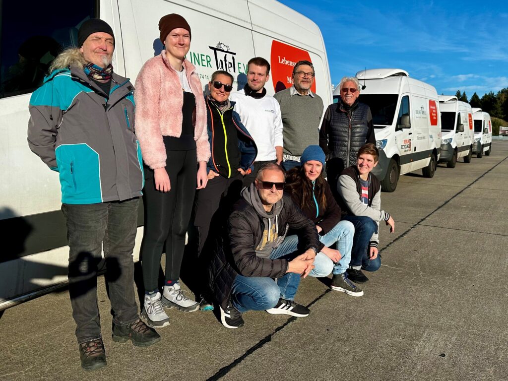 Tafel-Fahrer:innen posieren vor einem Fahrzeug der Berliner Tafel.