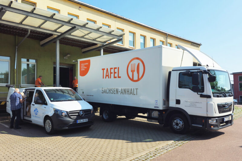 Das kleine Tafel-Auto steht neben dem großen Lkw der Tafel Sachsen-Anhalt. Wo kommen die Lebensmittel der Tafeln her? Aus dem Einzelhandel, abgeholt vom kleinen Auto, und aus dem Tafel-Lager des Landesverbandes.
