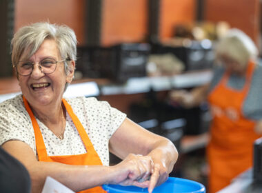 Eine fröhlich lachende Tafel-Helferin wringt einen Putzlappen aus.