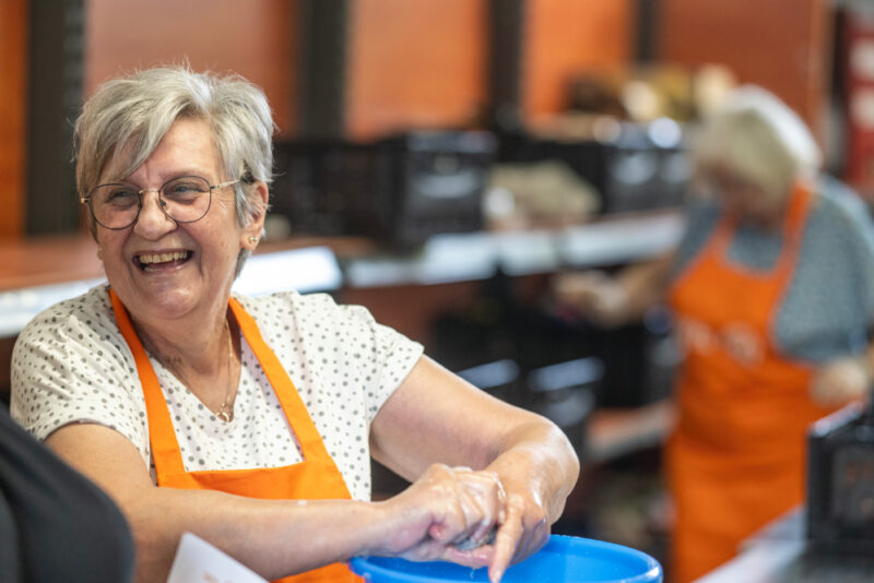 Eine fröhlich lachende Tafel-Helferin wringt einen Putzlappen aus.