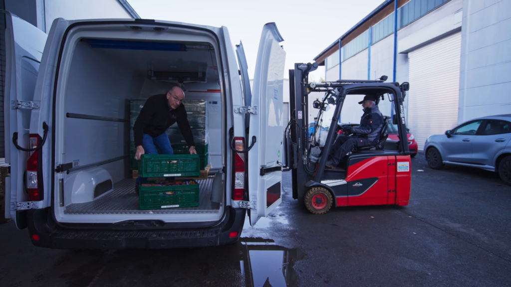 2 Tafel-Helfer beladen das Auto einer Tafel.