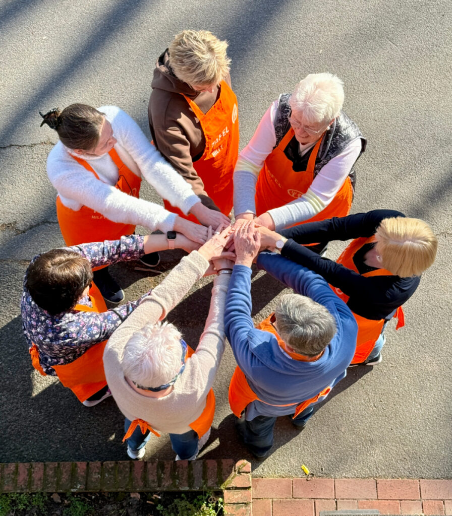 7 Tafel-Helferinnen legen ihre Hände im Zeichen der Solidarität zusammen.