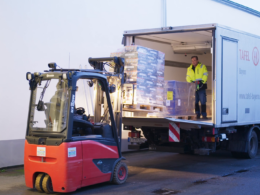 2 Tafel-Helfer laden Paletten mit haltbaren Lebensmittel aus einem Lkw aus.