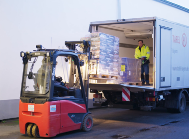 2 Tafel-Helfer laden Paletten mit haltbaren Lebensmittel aus einem Lkw aus.