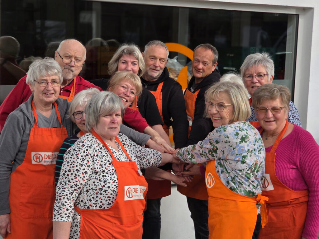 Das Donenrstagsteam der Tafel Niederberg legt lächelnd seine Hände zusammen, um für Vielfalt im Engagement einzutreten.