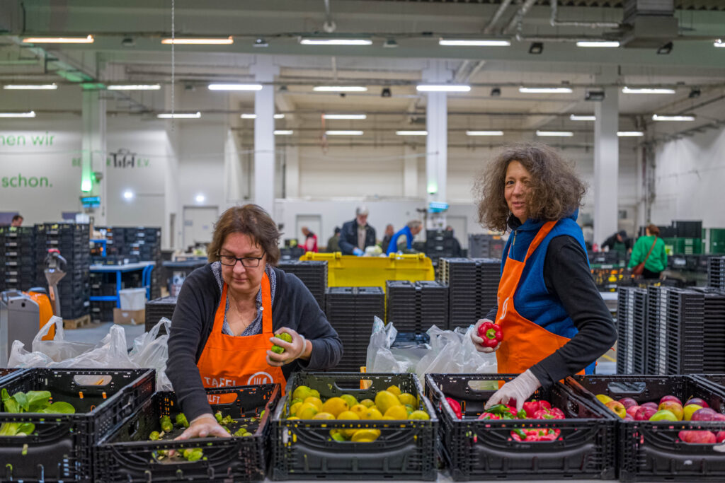2 Tafel-Helferinnen sortieren Lebensmittel bei der Berliner Tafel.