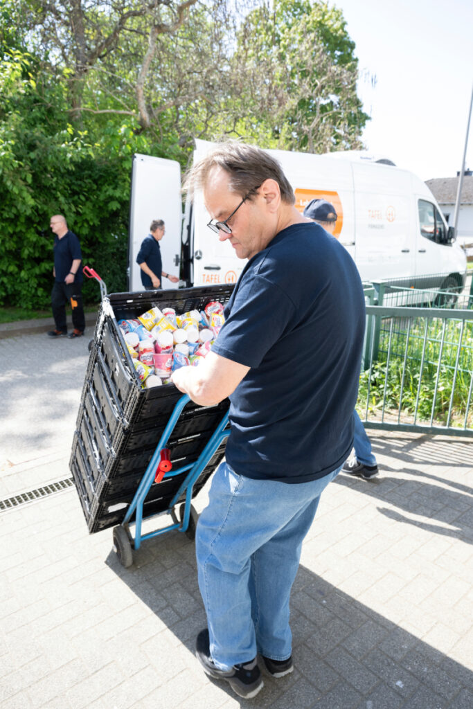Für die gesunde Tafel-Arbeit transportiert ein Engagierter Kisten auf einer Sackkarre.