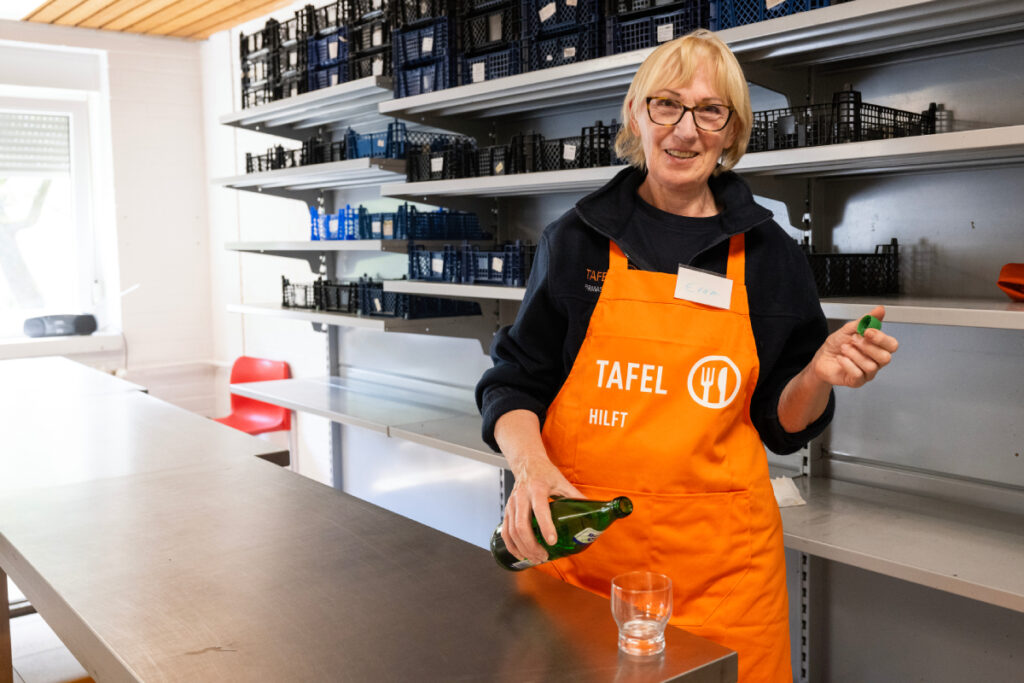 Eine Tafel-Helferin gießt sich ein Glas Wasser ein.