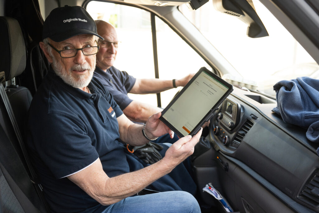 Ein beifahrer zeigt ein Tablet in die Kamera.