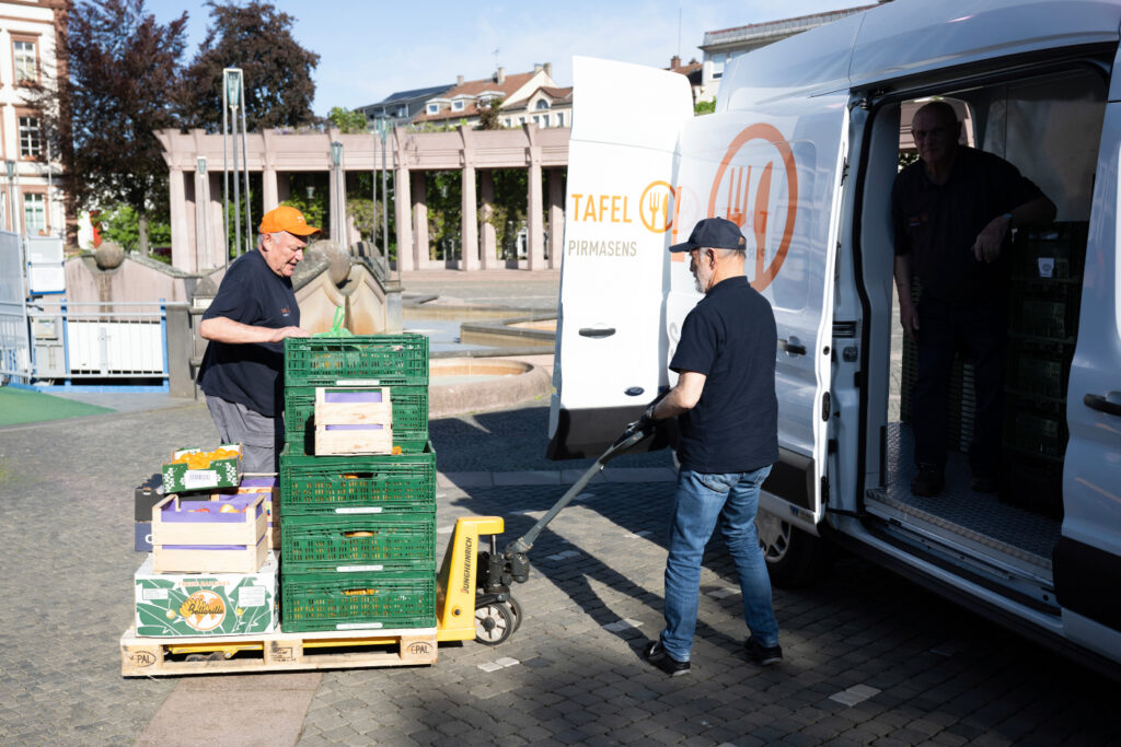 Mit einem Hubwagen fahren Tafel-Helfer Lebensmittelspenden zum Transporter.