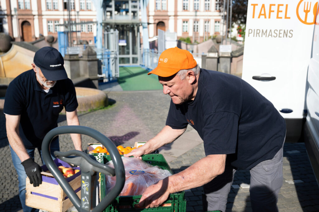 2 Tafel-Helfer der Pirmasenser Tafel beladen ihr Fahrzeug mit Obst und Gemüse.
