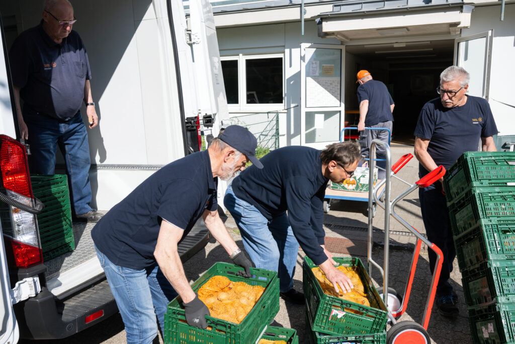 Tafel-Aktive laden Lebensmittelspenden aus einem Transporter vor dem Tafel-Gebäude.