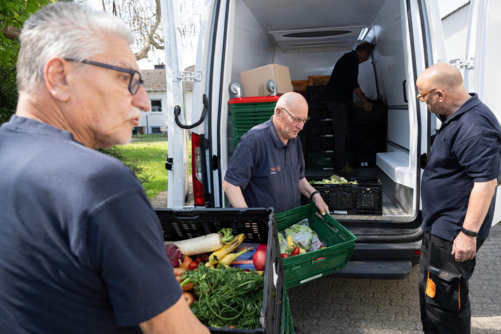 Tafel-Helfer laden Lebensmittel aus einem Fahrzeug aus.