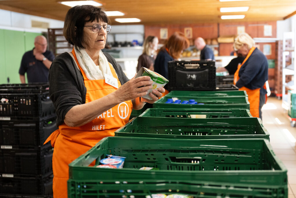Eine Tafel-Helferin kontrolliert das Mindesthaltbarkeitsdatum auf einer Packung Joghurt