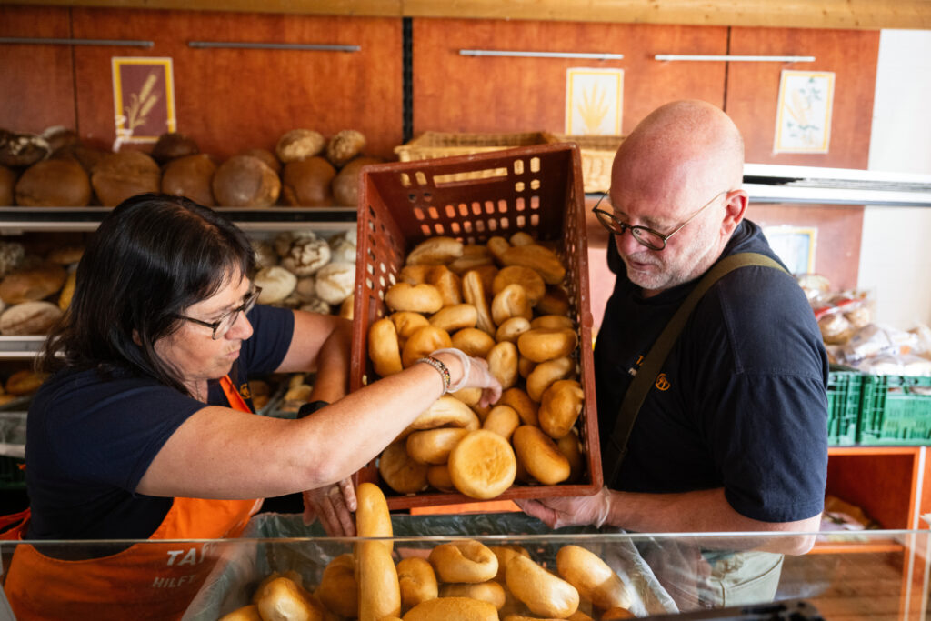 2 Tafel-Aktive schütten Brötchen in eine Kiste.